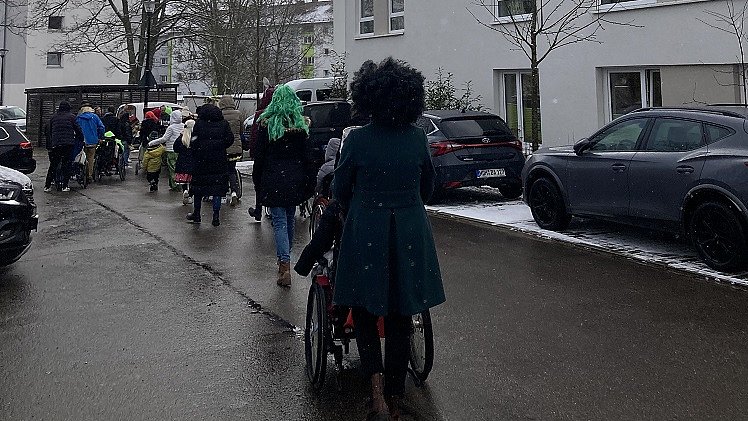Eine Gruppe Menschen und mehrere Rollstühle gehen und fahren eine Straße entlang.