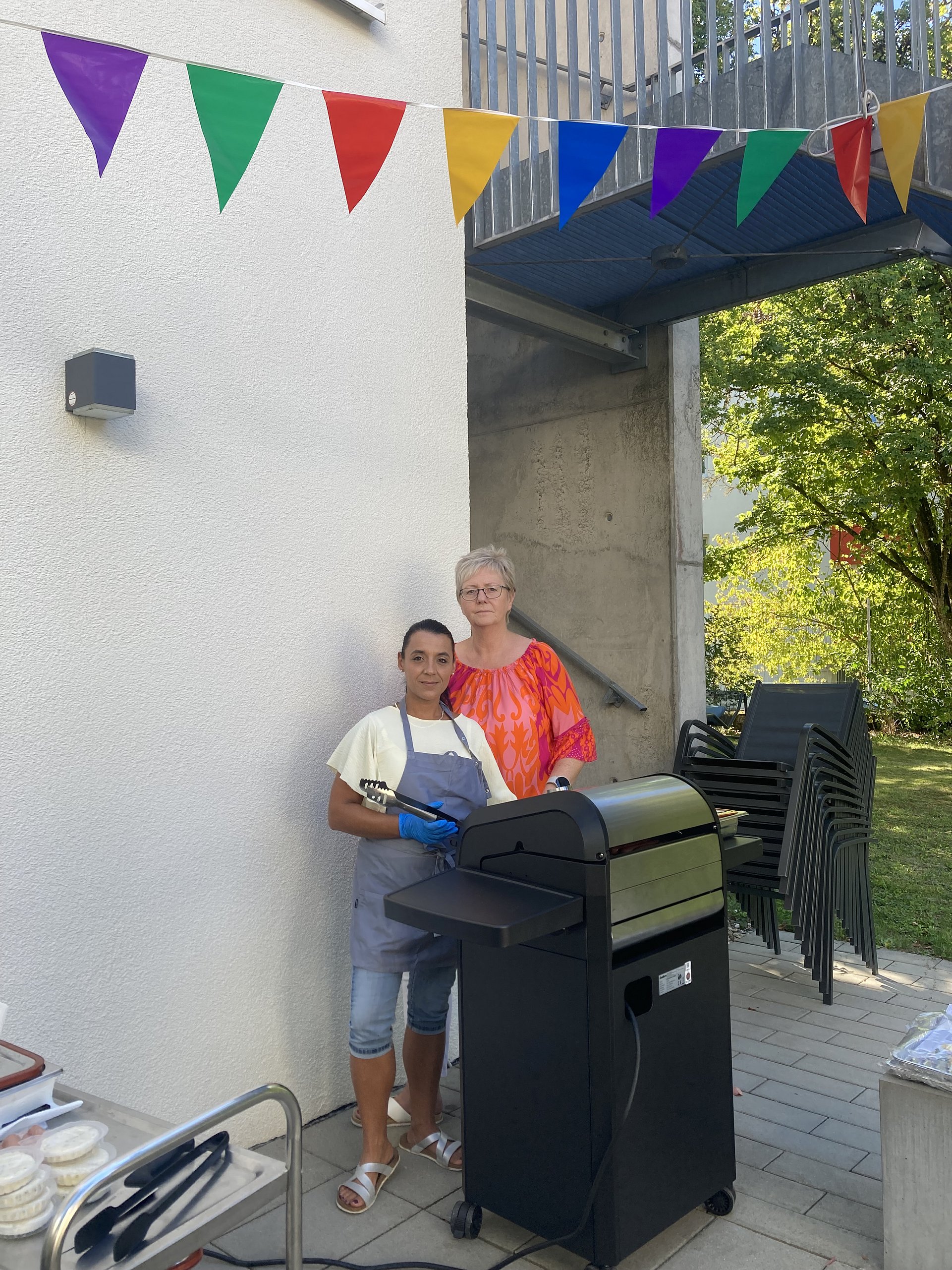 Zwei Frauen neben einem großen schwarzen Grillgerät.  