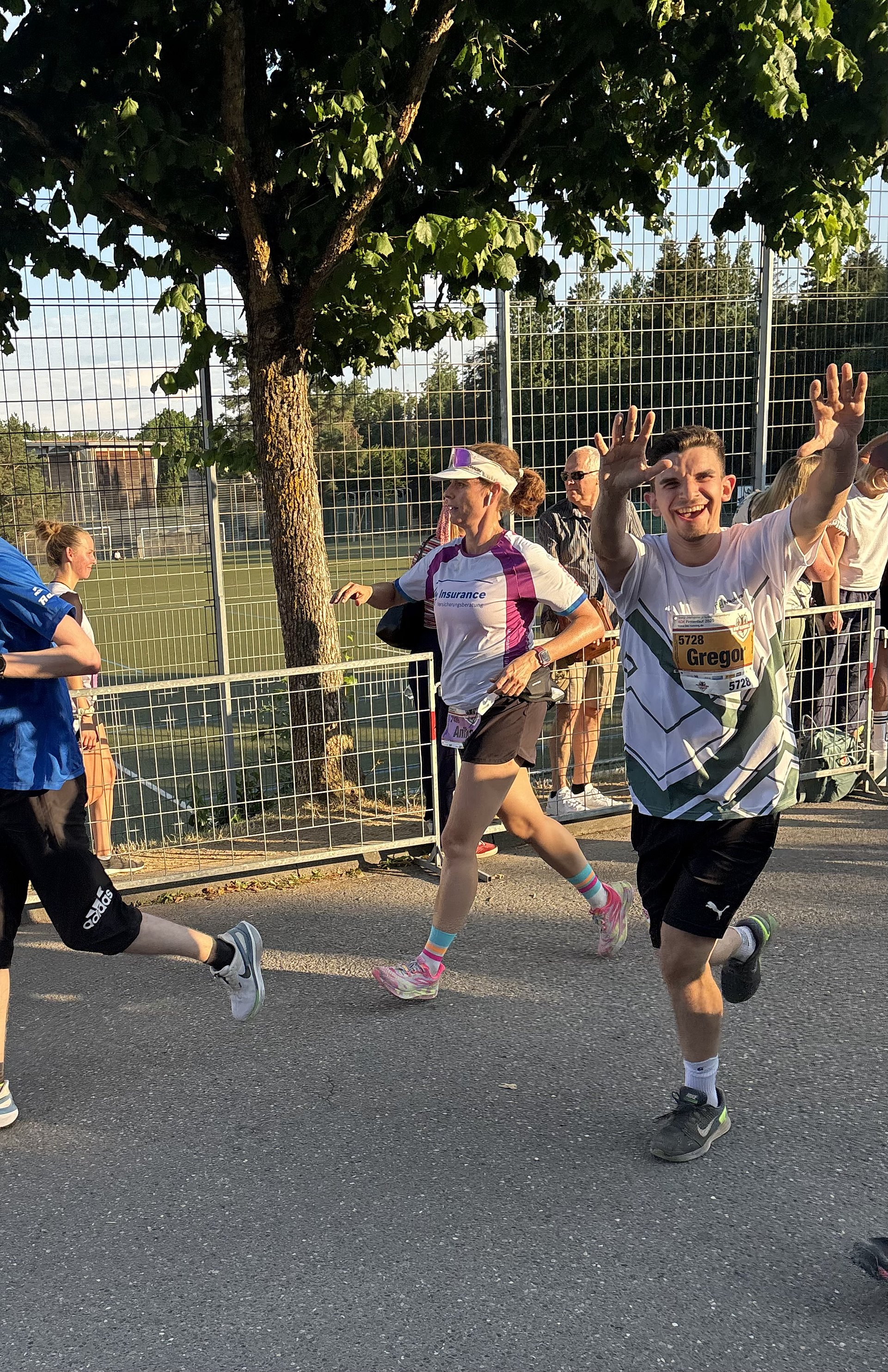 Bei einem Wettlauf auf einer Straße rennen viele Personen in Sportbekleidung nebeneinander.